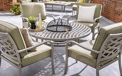 Image of Hartman Buxton 4 seat lounge set, with round firepit table surrounded by 4 cushioned metal chairs on a patio