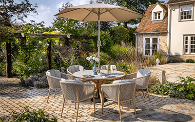 Hartman Portico 6 seat dining set, on a cobble stone patio in a cottage garden.