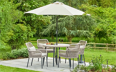 LG Panama 4 seater set, with 4 weave backed chairs, a round table and parasol, on a patio in a garden.