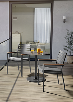 Close up of grey bistro set, with Metal backed chairs and grey aluminium round table top, glasses and wine on table with a plant